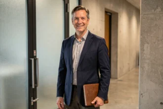 Portrait d'un homme élégant devant un studio de télévision, évoquant l'univers médiatique de France Télévisions