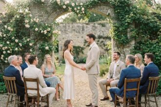 Couple échangeant leurs vœux lors d'un mariage intime en plein air avec quelques proches dans un jardin fleuri